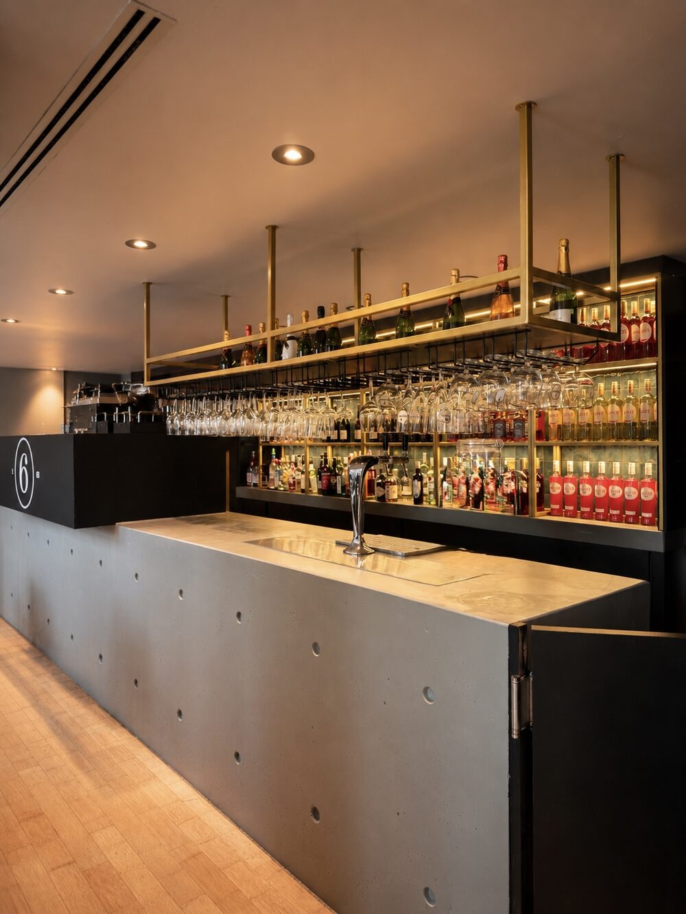 Bar mit hängenden Gläsern und goldenem Regal